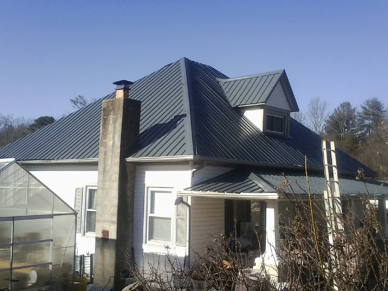 Dark blue standing seam metal roof on a white farmhouse with dormer — Slate & Tile Roof Repair by Roofing Brothers in Weatherford