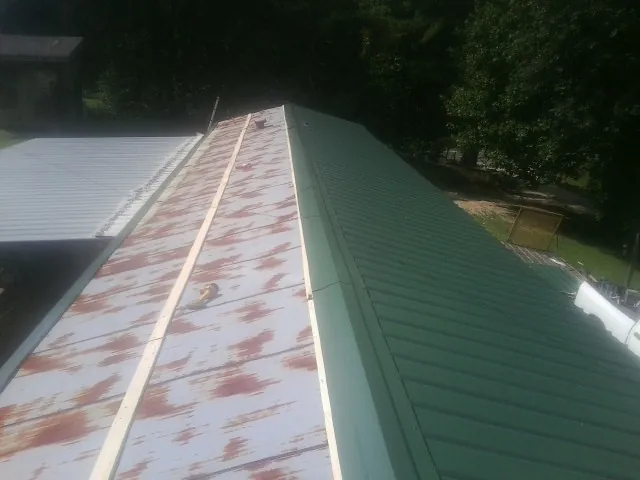 Old rusted panels beside newly installed green metal roofing — Wind Damage Roof Repair by Roofing Brothers in Weatherford