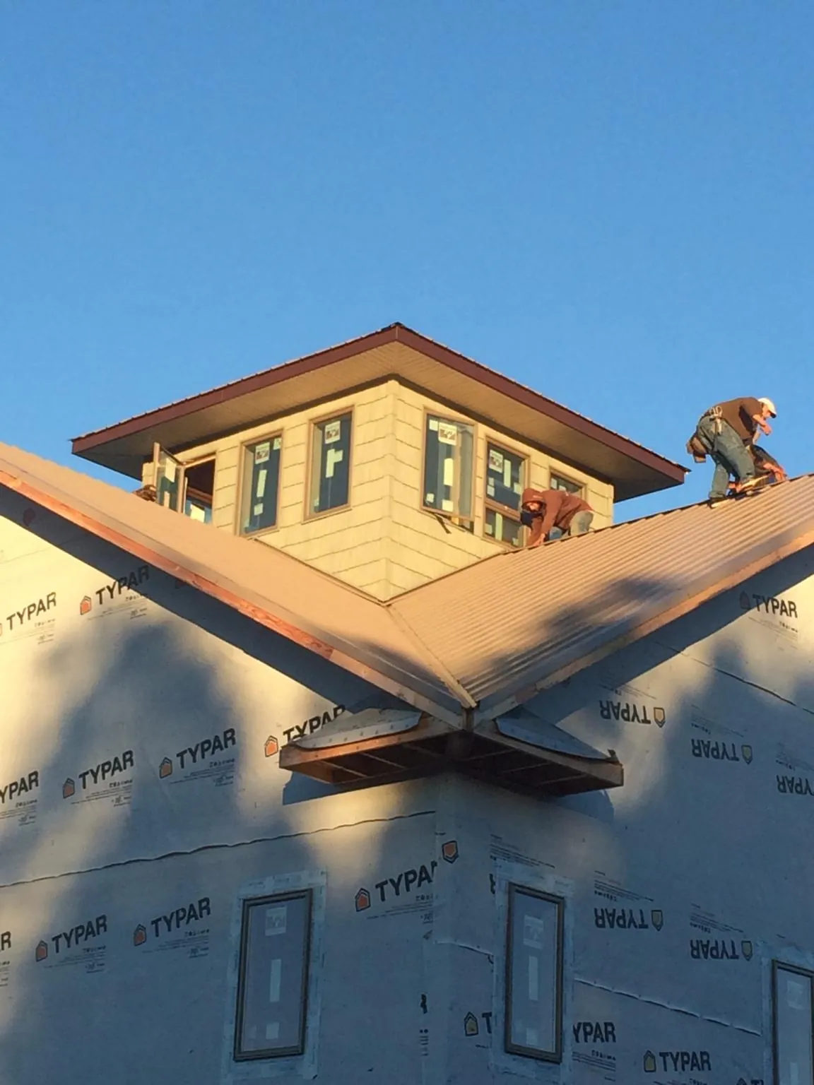 Roofers working around a rooftop cupola on a new metal roof at sunset — Roof Waterproofing in Weatherford by Roofing Brothers